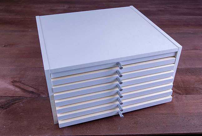 Schubladenschrank aus weiß-beschichteten MDF-Platten mit Schubladen aus Massivholz und aluminium Knöpfen